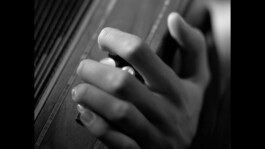 Black and white image showing a close up of a hand playing an instrument