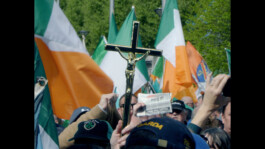 Irish flags and a Christian cross with crucified Jesus held up at a demonstration